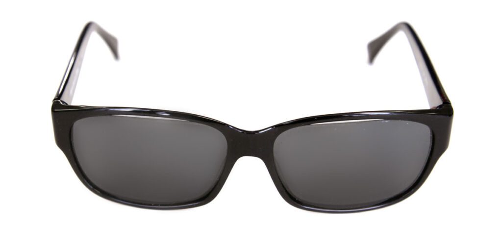 A pair of sunglasses with black frames and grey lenses.